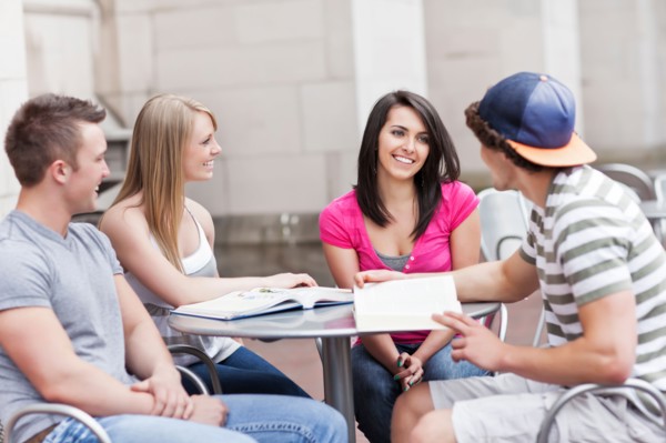 Four college students sitting at cafe table. Photo : Take A Pix Media