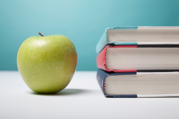 Studio shot of green apple and textbooks. Photo: Winslow Productions