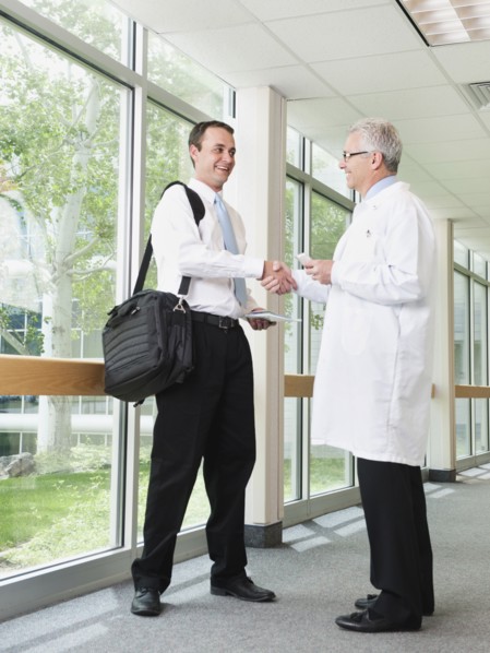 Doctor talking with pharmaceutical representative in hospital corridor.