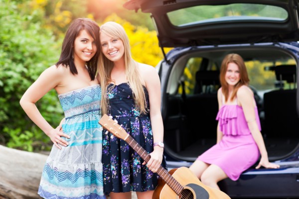 Portrait of young women with guitar by car. Photo: Take A Pix Media