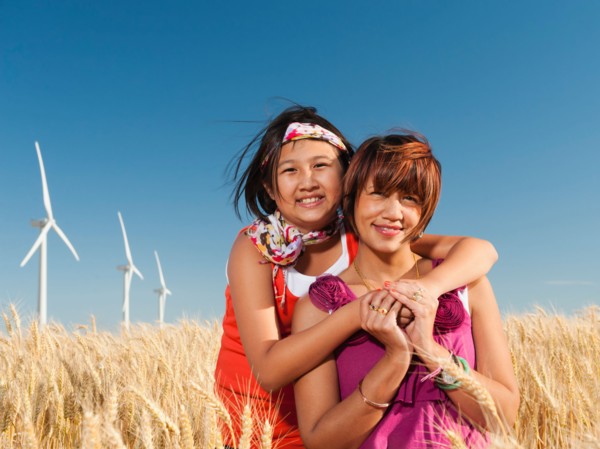 USA, Oregon, Wasco, Girl (10-11) and mother standing in wheat field in front of wind turbines.