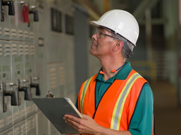 Industrial worker in hard hat writing on clipboard. Photo: db2stock