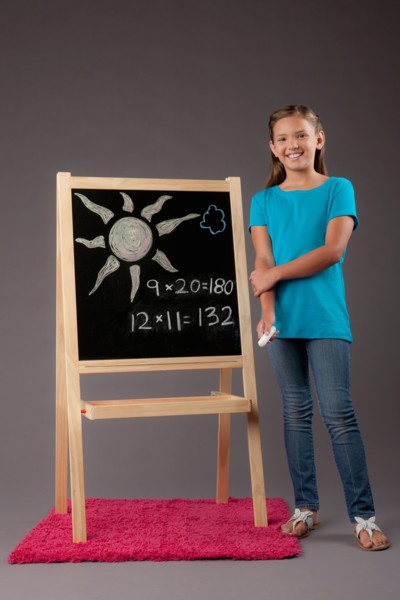 Studio portrait of girl (8-9) standing next to blackboard. Photo: Rob Lewine