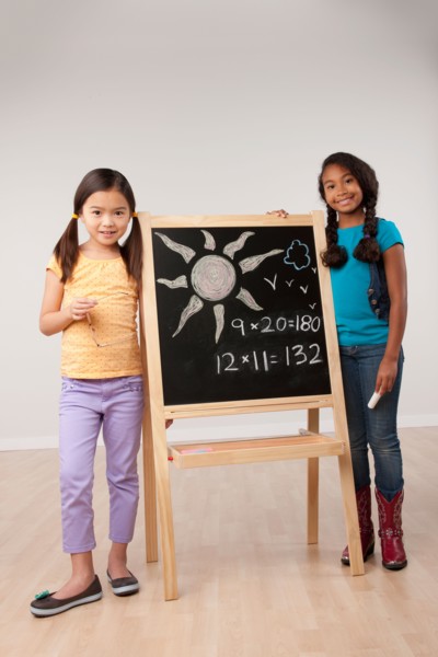 Studio portrait of two girls (8-9) standing by blackboard. Photo : Rob Lewine