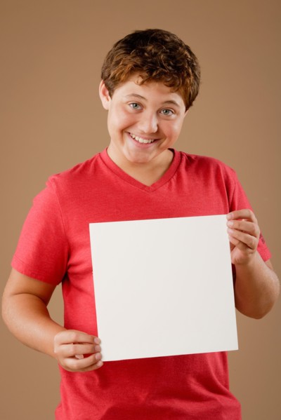 Studio portrait of boy (12-13) holding blank sheet of paper. Photo : Rob Lewine