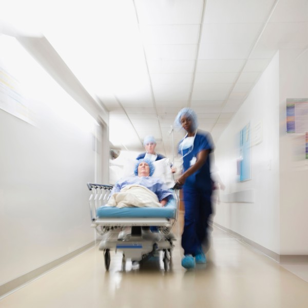 Senior woman being taken to operating room by medical staff.