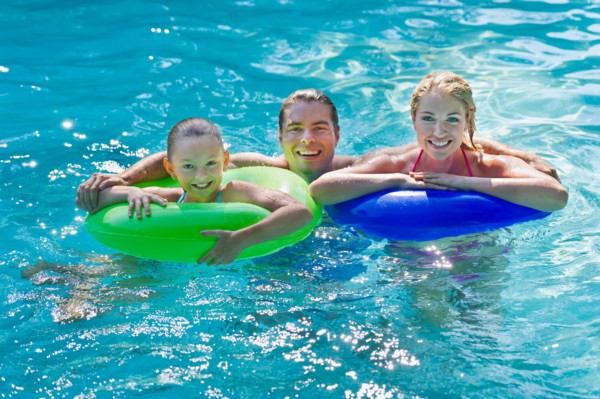 Girl (10-11) with parents in swimming pool.