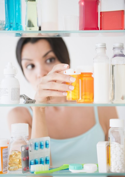 Woman taking medicine from cabinet. Photo: Jamie Grill