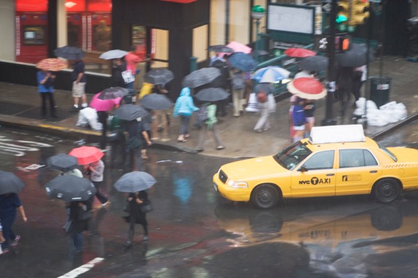USA, New York State, New York City, Manhattan, Yellow taxi cab on street, pedestrians walking with