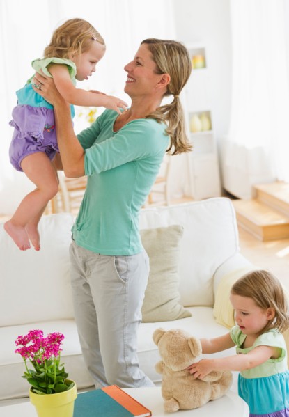 Mother playing with daughters (2-3) in living room.