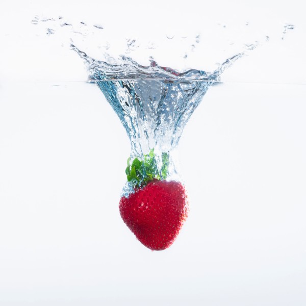 Strawberry splashing into water, studio shot. Photo : Daniel Grill