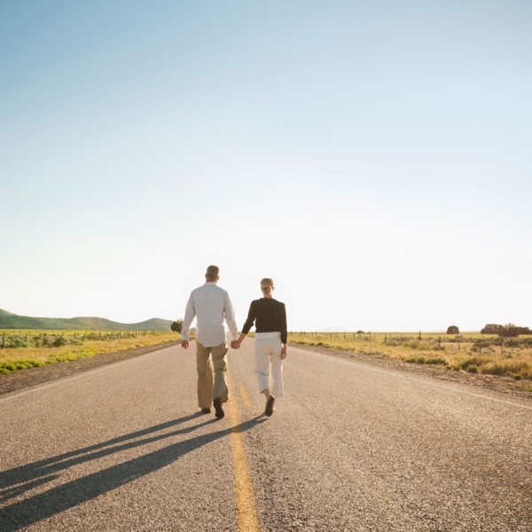 Mid adult couple walking along empty road . Photo: Erik Isakson