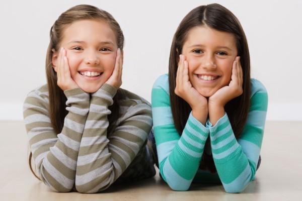 Studio portrait of two girls (8-9) lying on floor. Photo: Rob Lewine