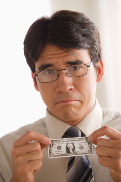 Sad business man holding one dollar note. Photo : Rob Lewine
