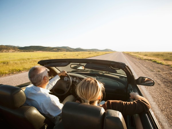 USA, Utah, Kanosh, Mad-adult couple driving through desert plains in convertible car. Photo: Erik