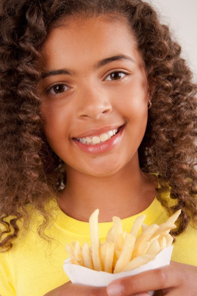 Studio portrait of girl (10-11) holding french fries. Photo: Rob Lewine