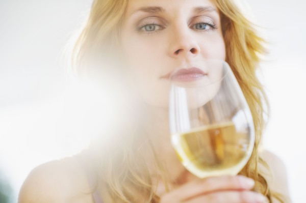Portrait of young woman smelling wine, studio shot.