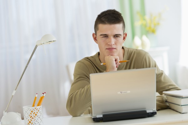 Boy (16-17) using laptop.