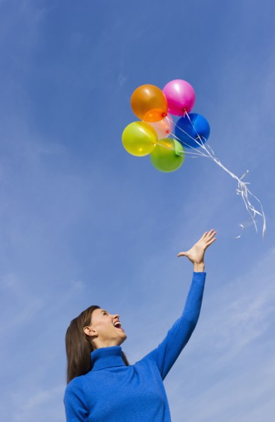 Smiling woman loosing balloons.