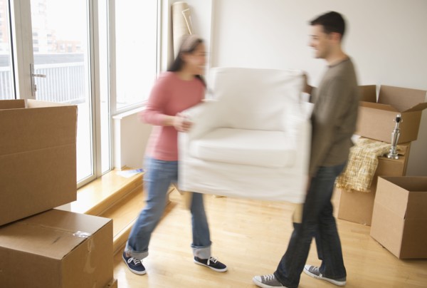 Man and woman carrying chair in new house.