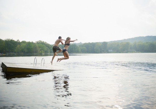 USA, New York, Putnam Valley, Roaring Brook Lake, Couple jumping from pier to lake. Photo : Jamie