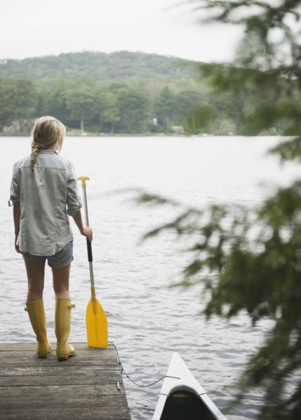 USA, New York, Putnam Valley, Roaring Brook Lake, Woman standing on pier with paddle. Photo : Jamie