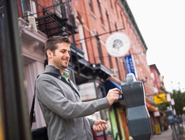 Man inserting coin to parking meter. Photo: Daniel Grill