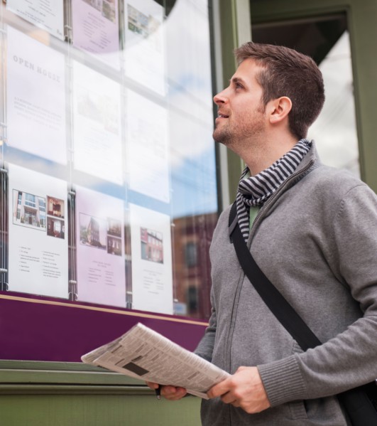 Man with newspaper looking at advert display. Photo: Daniel Grill