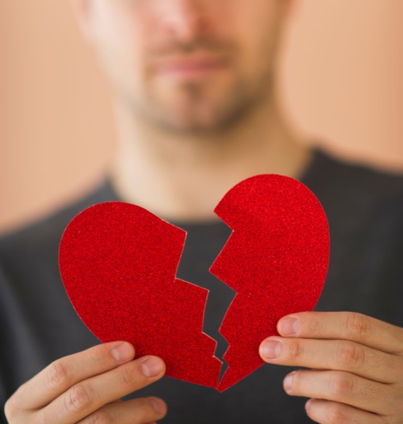 Young man holding broken paper heart. Photo : Daniel Grill