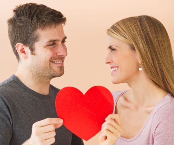 Couple holding red paper heart. Photo : Daniel Grill