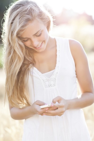 Teenage girl (16-17) text messaging outdoors. Photo : Take A Pix Media