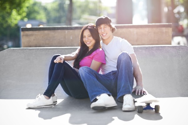 Young multi-racial couple posing with skateboard. Photo : Take A Pix Media