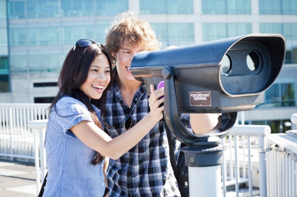USA, Washington, Seattle, Couple looking through coin-operated binoculars. Photo: Take A Pix Media