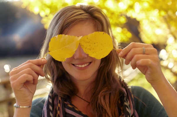 Woman covering eyes with autumn leaves. Photo: John Kelly