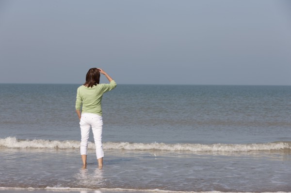 Woman on beach looking out to sea. Photo : Jan Scherders