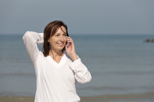 Woman on beach talking on phone. Photo : Jan Scherders