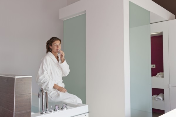 Woman in bathrobe sitting on tub. Photo : Jan Scherders