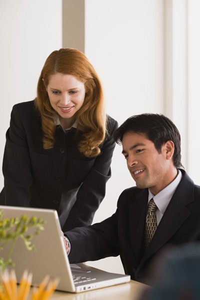 Businessman and businesswoman using laptop. Photo : Rob Lewine