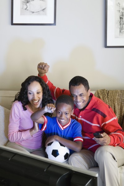 Parents with Son (12-13) watching sports on tv. Photo : Rob Lewine
