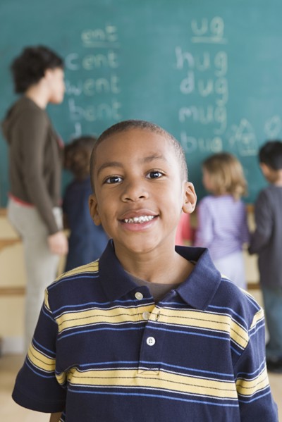 Portrait of boy (6-7) with schoolmates in background. Photo : Rob Lewine