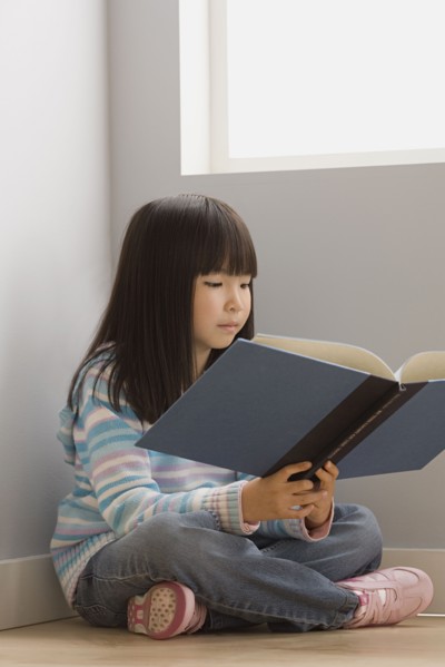 Girl (6-7) reading book in classroom. Photo: Rob Lewine