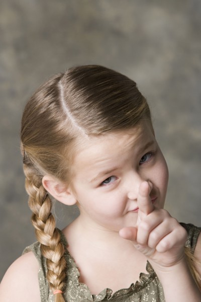 Portrait of smiling girl (8-9) pointing to camera, studio shot. Photo : Rob Lewine