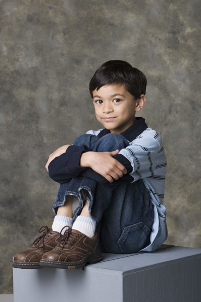 Smiling boy (8-9) standing, studio shot. Photo : Rob Lewine