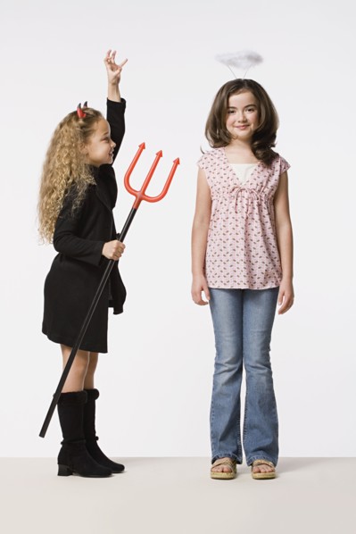 Two girls (8-9) dressed as angel and devil, studio shot. Photo : Rob Lewine
