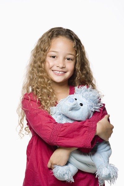 Portrait of smiling girl (8-9) embracing toy, studio shot. Photo : Rob Lewine