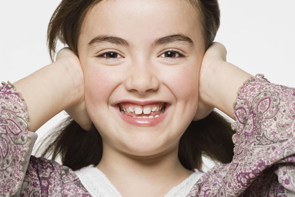 Smiling girl (8-9) covering her eyes, studio shot. Photo : Rob Lewine