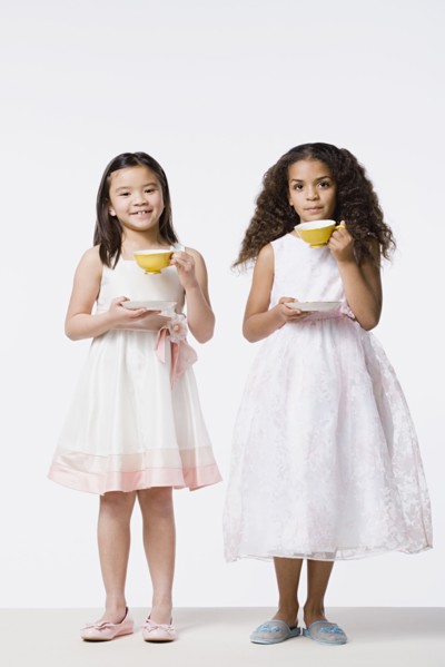 Two girls (8-9) wearing dresses and drinking tea, studio shot. Photo : Rob Lewine