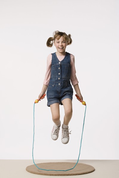 Studio portrait of girl (8-9) jumping on rope. Photo : Rob Lewine