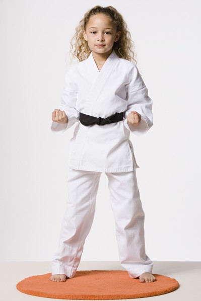 Studio portrait of smiling girl (8-9) wearing gi. Photo : Rob Lewine
