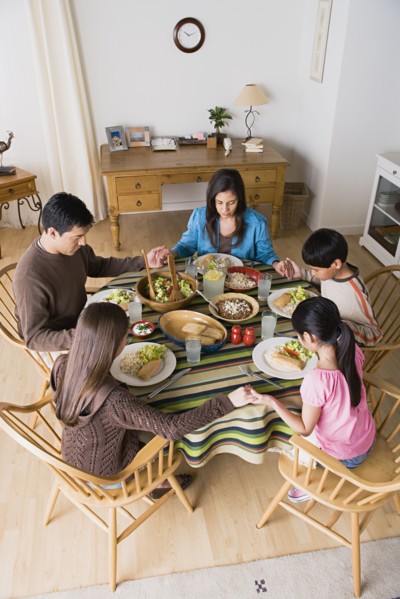 Family with three children (8-9, 10-11) praying at table. Photo : Rob Lewine